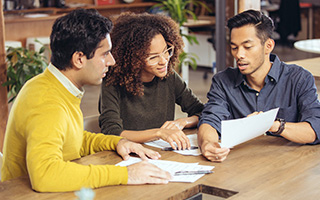 three people looking at documents